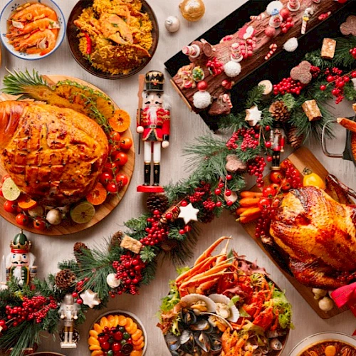 A festive spread featuring roasted meats, side dishes, desserts, garnished with holiday decorations and nutcracker figurines.