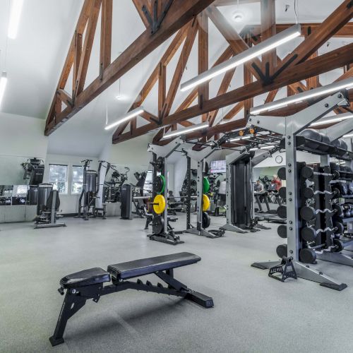 A modern indoor space with glass walls, lounge seating, and a few people walking; natural light floods the area from above.