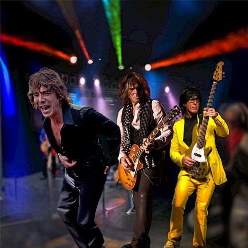 An image of three musicians performing on stage with colorful lighting. The musician in front appears to be singing, while the other two play guitar.
