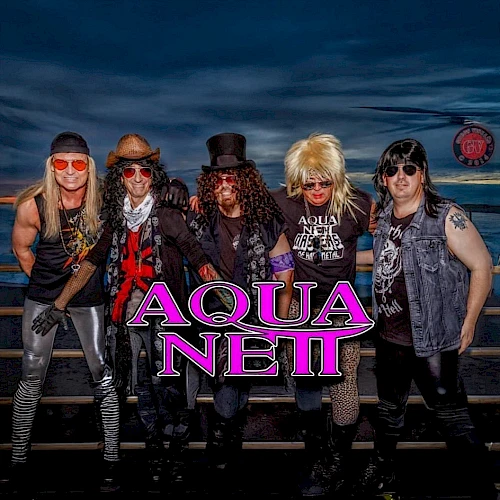 The image shows five people dressed in glam rock style with the text "Aqua Netl" in bold letters overlaid on the image.