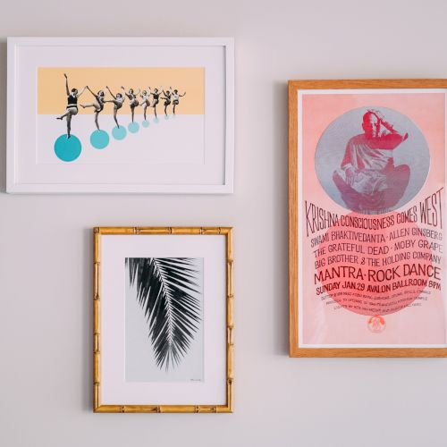 Three framed artworks are hung on a wall: a ballet illustration, a black palm leaf print, and a vintage-style dance poster.